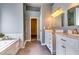 Light filled bathroom featuring double sinks, walk-in shower, garden tub, and marble countertops at 6921 Springbank Way, Stone Mountain, GA 30087