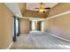 Large primary bedroom featuring tray ceiling with fan, neutral walls, and ample carpeted floorspace at 6921 Springbank Way, Stone Mountain, GA 30087