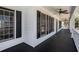 Spacious side porch with black painted wood floors, white wood facade, and ceiling fans at 7985 Thunder River Way, Cumming, GA 30028
