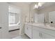 Bathroom featuring double vanity, white cabinets, and view into the adjacent bedroom at 3534 Diplomat Aly, Scottdale, GA 30079