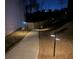 Backyard view featuring a concrete walkway illuminated with outdoor lighting, surrounded by grass and a wooden fence at 3836 Saddle Hill Way, Douglasville, GA 30135
