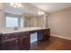 Main bathroom featuring a double vanity with dark cabinetry, hardwood floors, and a large mirror at 5414 Splendida Ct, Fairburn, GA 30213