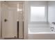 Clean white bathroom featuring a glass shower and a separate soaking tub near a window at 5414 Splendida Ct, Fairburn, GA 30213