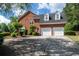 A side view of the red brick home showing a two car garage with driveway and manicured lawn at 772 Vinings Estates Se Dr, Mableton, GA 30126