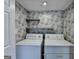 Charming laundry room with floral wallpaper, white appliances, and open shelving at 1335 Jamestowne Trl, Alpharetta, GA 30009