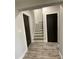 Hallway featuring grey wood-look floors with a view of the staircase and two black doors at 1888 Peeler Rd, Dunwoody, GA 30338
