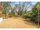 Large, dry backyard with sparse foliage, some trees, and a house in the background at 5915 Brookgreen Rd, Atlanta, GA 30328