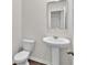 Bright bathroom featuring a pedestal sink, toilet, and a modern mirror at 1054 Mackets Ct, Atlanta, GA 30354