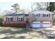 Charming home features a brick facade, white trim, a dark roof, and an attached two-car garage at 2110 E Cherokee Dr, Woodstock, GA 30188