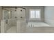 A beautifully tiled bathroom featuring a frameless shower and a soaking tub with a window view at 4296 Alba Ln, Buford, GA 30519