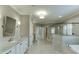 Spacious bathroom with dual sinks, a frameless shower, a soaking tub, and herringbone flooring throughout at 4296 Alba Ln, Buford, GA 30519