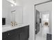 Modern bathroom featuring dark vanity with marble countertop, brass fixtures, and herringbone tile flooring at 155 Breakspear Ln, Fayetteville, GA 30214