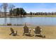 Picturesque pond view with three chairs on the grassy bank, perfect for relaxing outdoors at 155 Breakspear Ln, Fayetteville, GA 30214