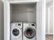 Laundry closet with a full size white front load washer and dryer at 156 Haven Oak Way, Lawrenceville, GA 30044