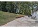 Grassy backyard with a stone patio, outdoor seating, a grill, and mature trees on a sunny day at 2418 Bolling Brook Sw Dr, Atlanta, GA 30311