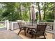 Outdoor kitchen features a grill, dining table, umbrella, and seating within a wooded back yard at 1308 Fairview Ne Rd, Atlanta, GA 30306