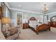 Bright main bedroom featuring an ornate bed frame, wainscotting, and a chandelier at 3816 Turnberry Ct, Duluth, GA 30096
