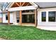 A covered patio features a stone fireplace, wood beams, and stone flooring, offering an inviting outdoor space at 6110 Harvest Way, Cumming, GA 30028