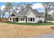 A well-manicured lawn surrounds a white brick home with black-framed windows and a charming covered porch at 6110 Harvest Way, Cumming, GA 30028
