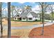 New construction shows off a bright white exterior, well-manicured lawn, and gravel driveway at 6110 Harvest Way, Cumming, GA 30028