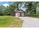 Two car detached garage with a gravel driveway surrounded by green grass and mature trees at 6110 Harvest Way, Cumming, GA 30028