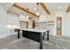 Spacious kitchen featuring a large island with marble countertop, custom cabinets, and wooden beam accents at 6110 Harvest Way, Cumming, GA 30028