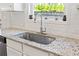 Kitchen sink with a granite countertop, white cabinets, and a view to the backyard through the window at 311 Ivy Chase Loop, Dallas, GA 30157
