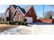 Side view of red brick home with a large driveway and attached garage, complemented by lush landscaping at 5289 Browning Sw Way, Lilburn, GA 30047
