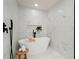 Bright bathroom featuring a freestanding tub, stone tile floor, black fixtures, and a marble-look tile wall at 6405 Cherry Tree Ln, Atlanta, GA 30328