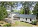 Charming home with neutral siding, dark roof, and a partially fenced front yard, surrounded by mature trees at 6405 Cherry Tree Ln, Atlanta, GA 30328