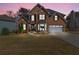 Charming brick home with manicured lawn, two-car garage, and an illuminated front entrance at dusk at 1264 Ridge Vista Nw Ct, Lawrenceville, GA 30043