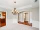 Elegant dining area with a decorative chandelier, neutral carpet, and trim; kitchen partially visible in the background at 2848 Stockbridge Way, Dacula, GA 30019