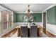Stylish dining room with green walls, hardwood floors, a modern chandelier, and wainscoting at 5114 Parkwood Oaks Ln, Mableton, GA 30126