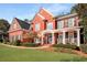Stunning two-story red brick home featuring a welcoming front porch and lush landscaping at 5114 Parkwood Oaks Ln, Mableton, GA 30126