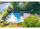 Community pool with lounge chairs and tables, surrounded by lush landscaping and trees with lake in background at 2702 Long Lake Ne Ter, Roswell, GA 30075