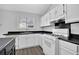Bright kitchen featuring white cabinets, black countertops, and wood floor at 3954 Springleaf Pt, Stone Mountain, GA 30083