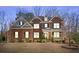 Beautiful two-story brick house featuring illuminated windows, a porch, and manicured shrubs at 6040 Ashborough Park, Cumming, GA 30040