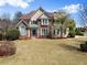 Charming two-story home with stone accents, a manicured lawn, and vibrant landscaping at 12350 Broadleaf Ln, Johns Creek, GA 30005