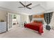 Main bedroom featuring french doors, a ceiling fan, tray ceiling, and a large red bed at 12350 Broadleaf Ln, Johns Creek, GA 30005