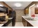 Functional kitchen with brick accent wall, tile floors, black appliances, and ample cabinet space at 6 Nw Fairway Nw Dr, Kennesaw, GA 30144