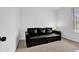 Cozy bedroom featuring a black leather sofa, white walls, and a window with metal security bars at 4663 Hairston Crossing Pl, Stone Mountain, GA 30083