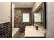 Bathroom with brick accent wall, white tub, vanity, and mirror at 584 Cherokee Ne St, Marietta, GA 30060