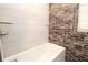 A modern bathtub with white tiling and dark brick accents on the wall at 584 Cherokee Ne St, Marietta, GA 30060