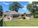 View of the home's exterior featuring an enclosed porch, lawn, and mature trees on a sunny day at 584 Cherokee Ne St, Marietta, GA 30060