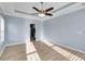 This primary bedroom features light blue walls, tray ceilings, light wood floors and a ceiling fan with light fixture at 363 Safe Harbor Dr, Dallas, GA 30157