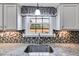 Close-up of the kitchen sink with granite counters, mosaic backsplash, and shaker cabinets at 363 Safe Harbor Dr, Dallas, GA 30157