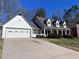 View of the home showing its white siding, green trim, and a spacious driveway leading to an attached garage at 3750 Clubhouse Se Ln, Conyers, GA 30094