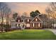 Charming brick home with a manicured lawn and inviting front porch, showcasing a serene sunset backdrop at 4140 Hillsborough, Cumming, GA 30041
