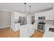 This modern kitchen features white cabinets, hardwood floors, stainless appliances, and an island with a white countertop at 4140 Hillsborough, Cumming, GA 30041
