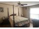 Spacious bedroom with a four poster bed, floral comforter, ceiling fan, and view of the backyard at 53 Oakview Dr, Carrollton, GA 30116